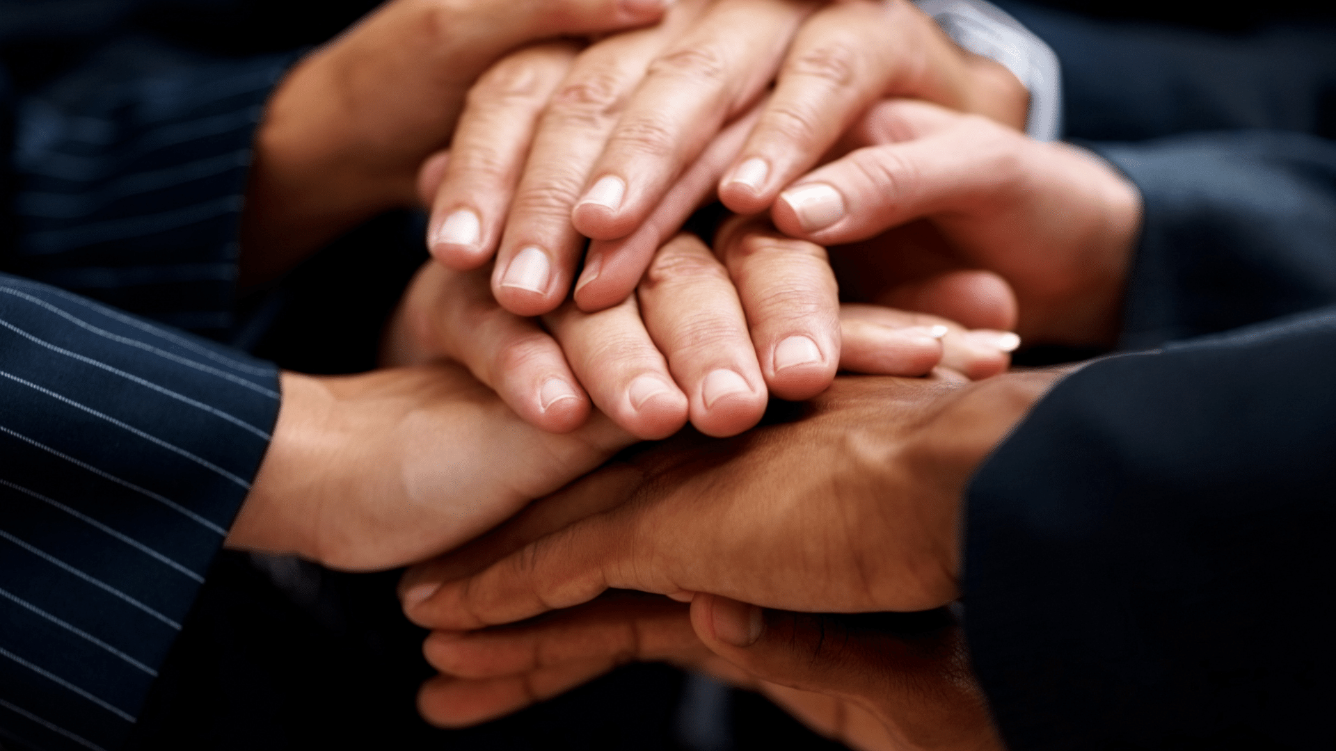 group of hands from various skin tones stacked together